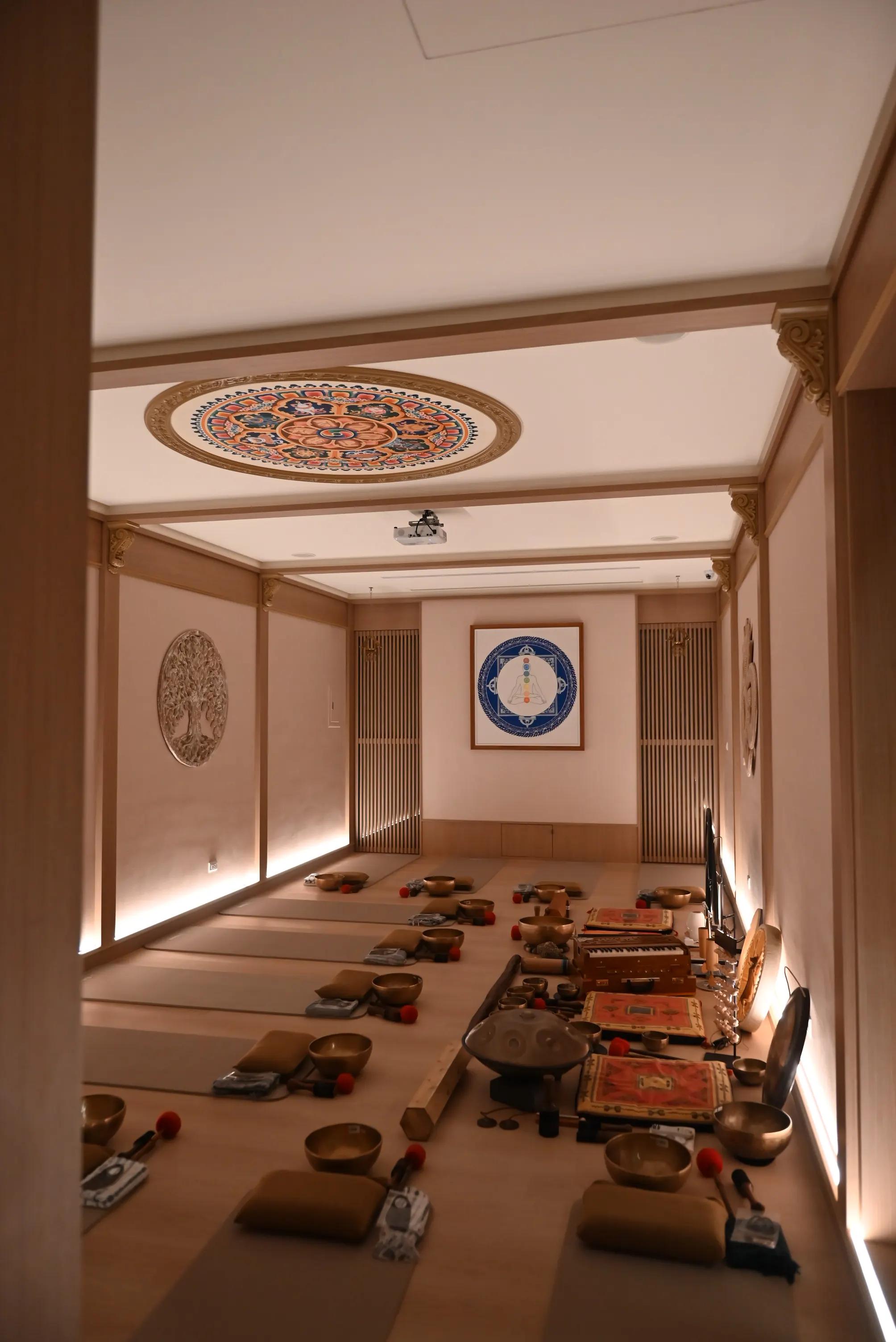 Meditation hall set up for sound bath with singing bowls on yoga mats